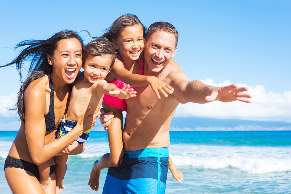 A young family smiles at the beach, one of the many things to do in Palm Harbor, FL.