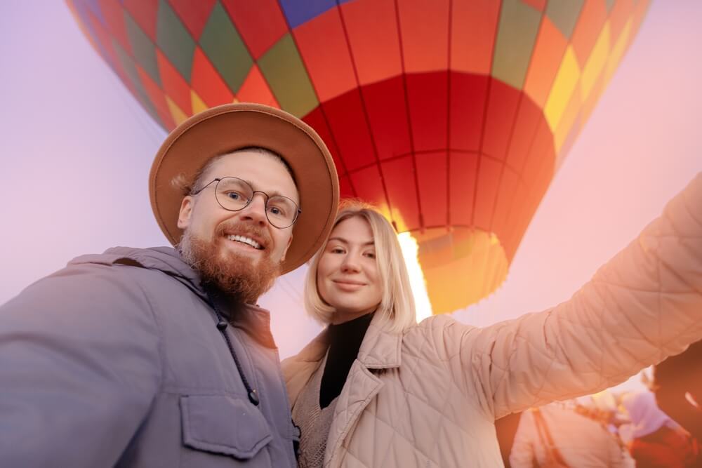 Romantic Things to Do in Scottsdale, AZ: A young couple smiles into the camera with a hot air balloon in the background.