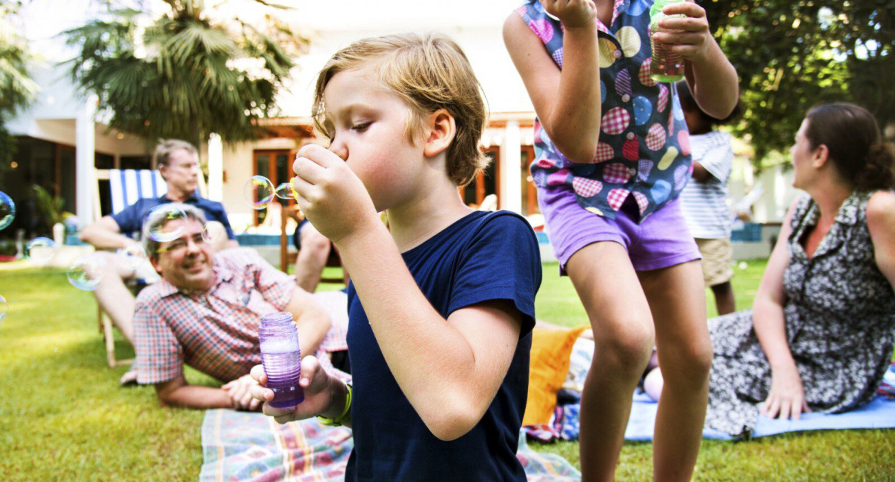 A youngster blowing bubbles while enjoying a family reunion venue.